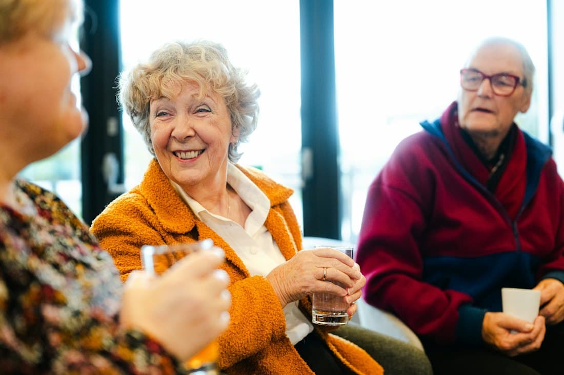 Seniors talking and smiling together in a community lounge